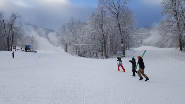 Des skieurs marchent au bas des pentes de ski.