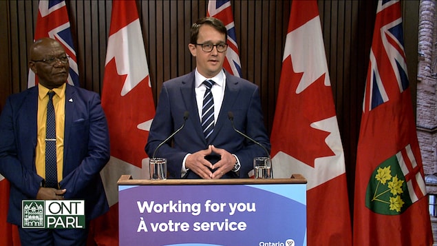وزير العمل والهجرة في أونتاريو، مونتي ماكنوتون، يتحدث واقفاً خلف منبر.