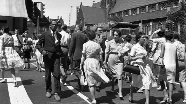 Des passants traversent l'intersection achalandée des rues Sainte-Catherine et Université, à Montréal, en 1963. Des passants traversent l'intersection achalandée des rues Sainte-Catherine et Université, à Montréal, en 1963.