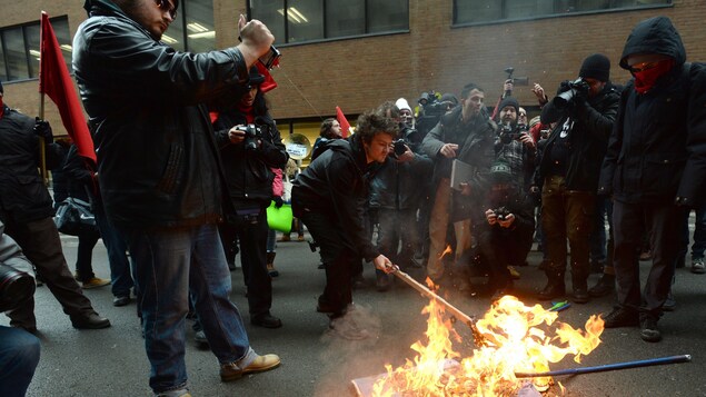 Dans les rues du centre-ville de Montréal, des manifestants anti-Trump brûlent un drapeau américain le 20 janvier 2017. Dans les rues du centre-ville de Montréal, des manifestants anti-Trump brûlent un drapeau américain le 20 janvier 2017.