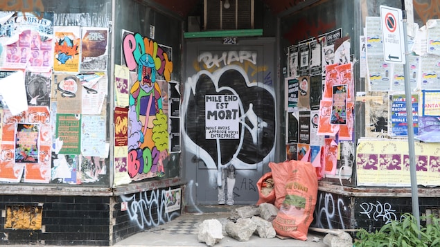 La devanture d'un commerce désaffecté est recouverte d'affiches et de graffitis.