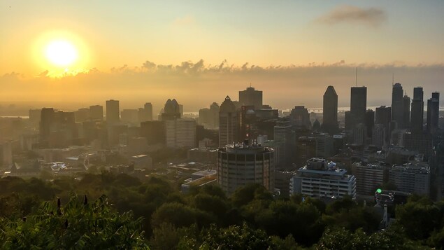 Lever de soleil sur Montréal avec quelques nuages par une chaude journée d'été. Vue du parc du Mont-Royal.