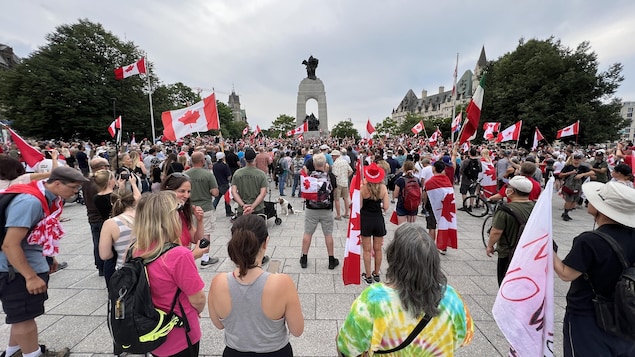 A large crowd of people gathers at the National War Memorial in Ottawa on June 30, 2022, to mark the arrival of veteran James Topp. Topp marched across Canada as part of a protest against remaining COVID-19 vaccine mandates. 