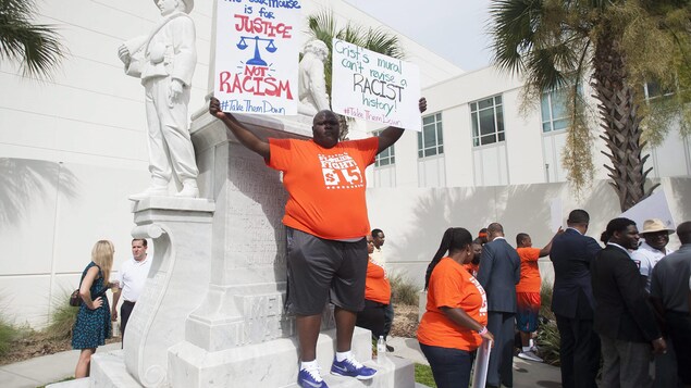 Un homme brandit une pancarte sur laquelle on peut lire : "Le palais de justice n'est pas pour le racisme." Un homme brandit une pancarte sur laquelle on peut lire : "Le palais de justice n'est pas pour le racisme."