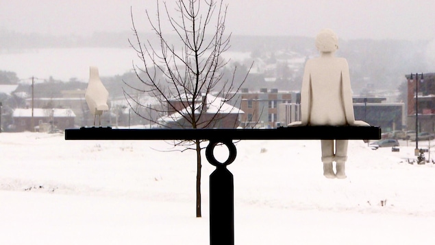 Un monument représentant un enfant et un oiseau regardant au loin.