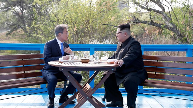 Moon Jae-in et Kim Jong-un discutent en tête-à-tête autour d'une petite table en bois. Moon Jae-in et Kim Jong-un discutent en tête-à-tête autour d'une petite table en bois.