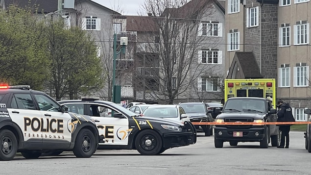 Des voitures de police devant un immeuble à logements.
