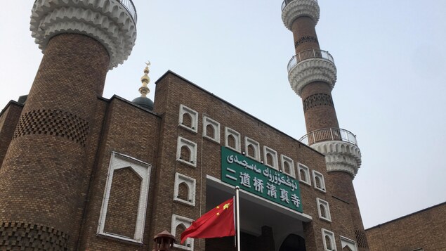 العلم الصيني يرفرف أمام مسجد في أورومتشي، عاصمة إقليم شينجيانغ في شمال غرب الصين.