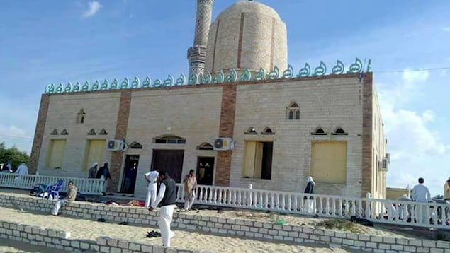 Des gens marchent devant une mosquée.