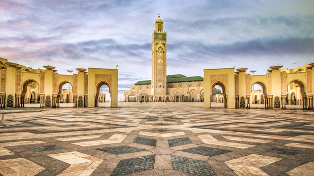 Une grande place pavée vide devant une mosquée au toit et au minaret vert. Une grande place pavée vide devant une mosquée au toit et au minaret vert.