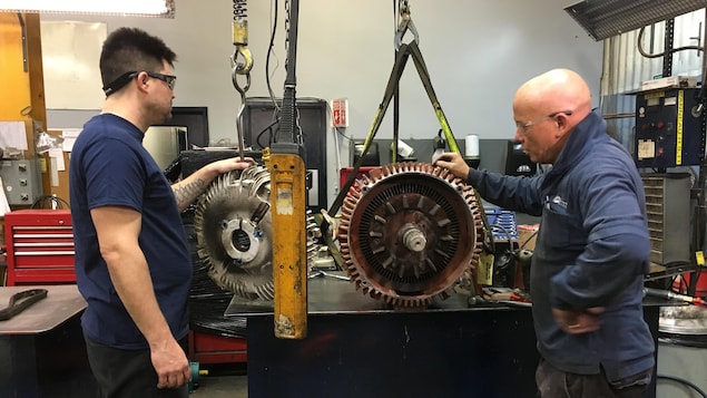 Un homme devant un moteur dans un atelier. Un homme devant un moteur dans un atelier.