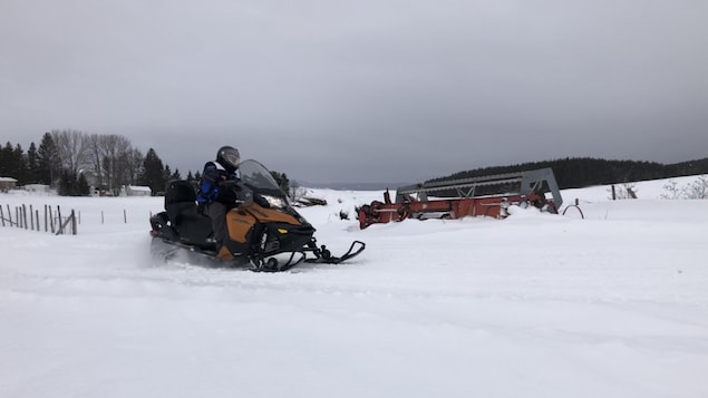 Une motoneige dans un sentier. De la machinerie agricole.