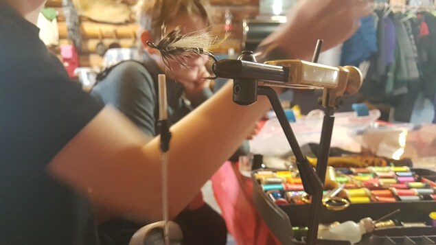 Une mouche à pêche est placée dans un étau afin de terminer le montage des différents matériaux. 