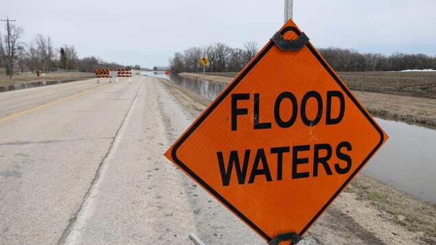 Des panneaux indiquent que la route provinciale 200 est fermée en raison des inondations, le lundi 9 mai 2022. On voit au loin de l'eau qui traverse la route.