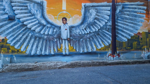 Un garçon habillé d'un costume blanc porte des ailes d'ange.  