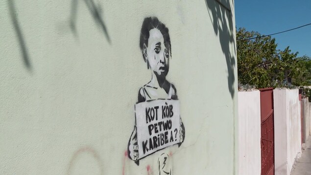 Une murale à Port-au-Prince montrant une petite fille tenant une affiche faisant référence au scandale PetroCaribe en Haïti.