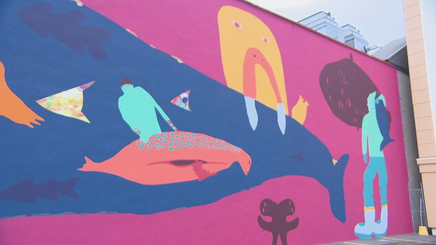 Une murale de couleurs rose, orange et bleu où sont représentés des animaux marins Une murale de couleurs rose, orange et bleu où sont représentés des animaux marins