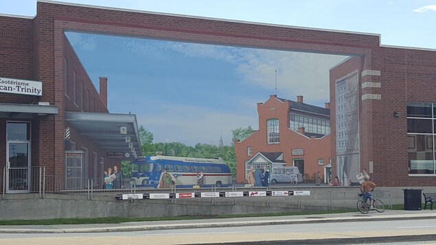Un terminus d'autobus en trompe-l'oeil sur un mur de briques rouges.