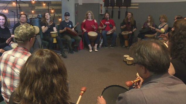 Un groupe de personnes est assis en cercle avec des tambours et des djembés. Un groupe de personnes est assis en cercle avec des tambours et des djembés.