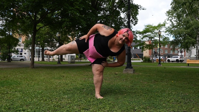 Une femme en tenue sportive en position de sumo dans un parc