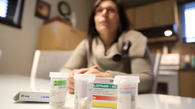 Nancy Laporte, victime d'agressions sexuelles et atteinte de fibromyalgie, pose derrière des médicaments.