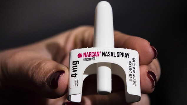 Une main tient le spray nasal Narcan.