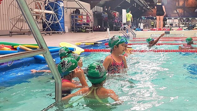 Huit enfants sont dans une piscine et apprennent à nager