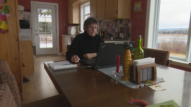 Nathalie Dubé assise à une table devant son ordinateur.
