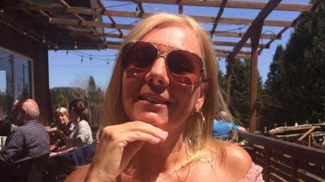 Une femme souriante en vacances, assise à une table.