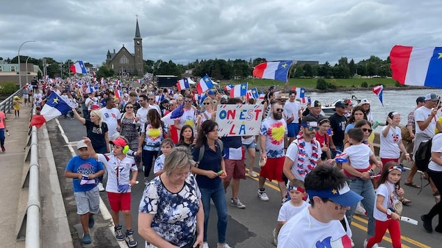 A gathering of people sporting Acadian shirts and flags.