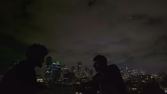 Deux hommes parlent dehors la nuit.