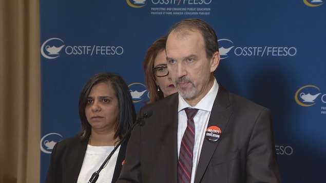 Un homme sur un podium en conférence de presse.
