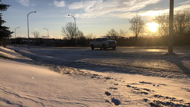 Un camion passe sur une route enneigée lors du lever du soleil.