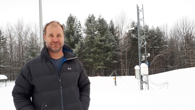Le professeur Alexandre Langlois pose devant une forêt et des instruments de mesure.