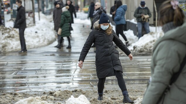 Une Torontoise soulève une botte pour ne pas marcher dans une mare d'eau glacée au centre-ville.