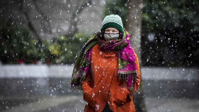 Une femme marche sous un épisode neigeux.