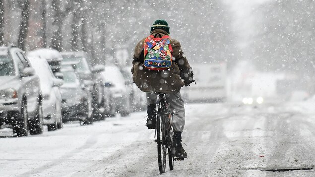 Une personne à vélo sous la neige à Montréal.