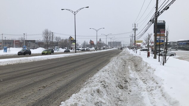 Des véhicules circulent sur une route de Chicoutimi en hiver.