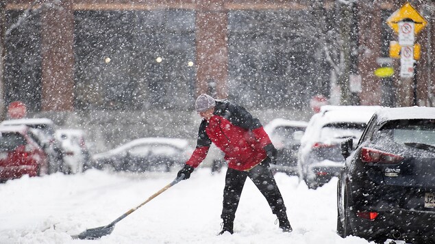 Un homme déneige sa voiture.