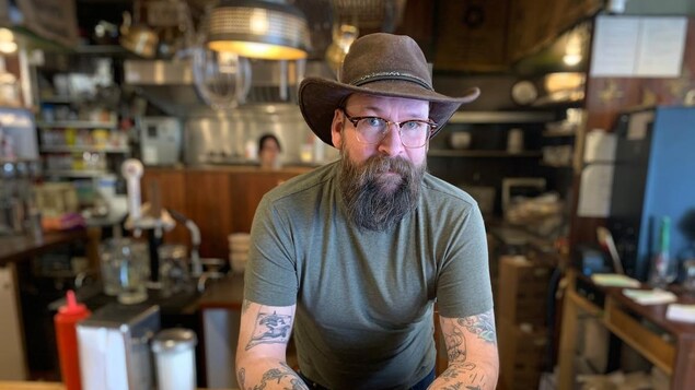 Dans le restaurant, un homme fixe l'objectif. L'émotion se lit dans son regard.
