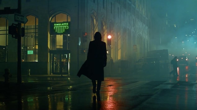 Neo marche de dos sous la pluie dans une rue d'une grande ville.