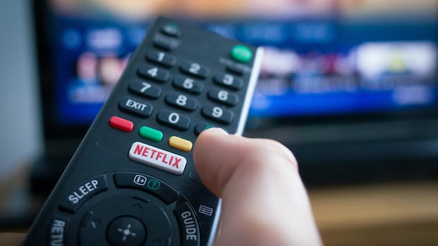 Une télécommande sur laquelle apparaît un bouton « Netflix » est pointée vers un téléviseur.