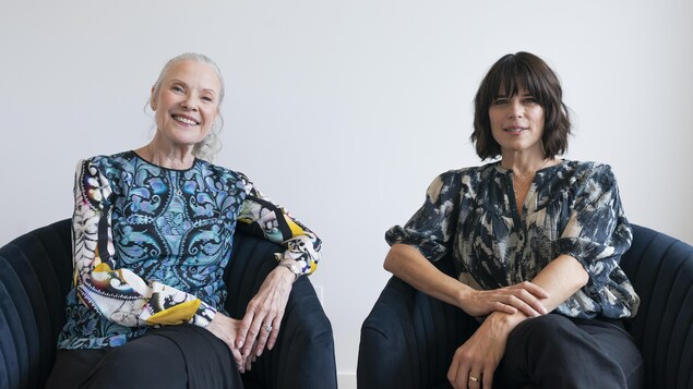 Les deux femmes sourient, assises côte à côte, sur des fauteuils. 