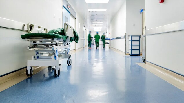 Isang hallway sa loob ng ospital kung saan nakatayo ang ilang health-care staff.
