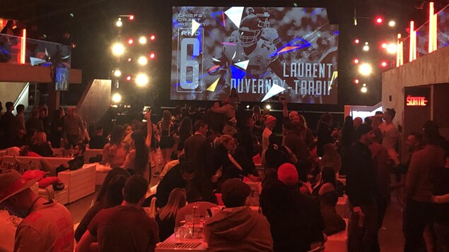 Un grand écran dans un bar montre une photo de Duvernay-Tardif.