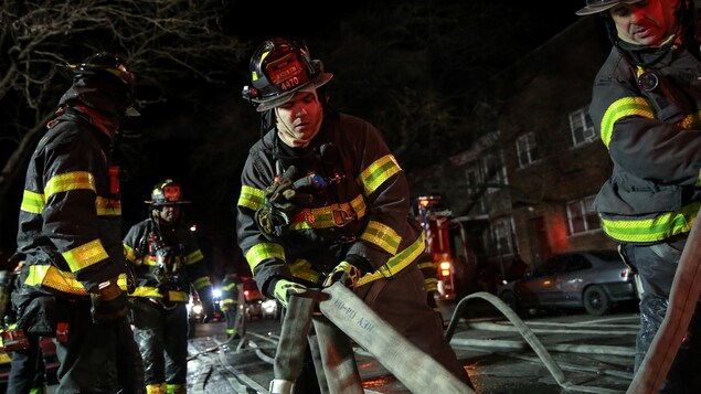 Des pompiers déroulent des boyaux d'incendie. Des pompiers déroulent des boyaux d'incendie.