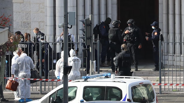De nombreux policiers se trouvent derrière un cordon de sécurité devant la porte de l'église.
