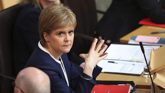 La première ministre écossaise Nicola Sturgeon assise à un bureau au parlement. La première ministre écossaise Nicola Sturgeon assise à un bureau au parlement.