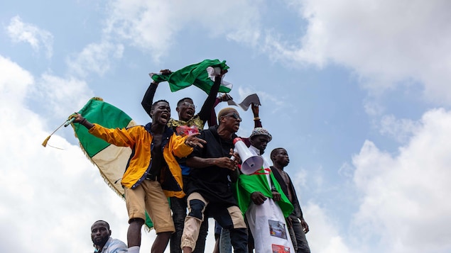 Des jeunes crient et agitent des drapeaux.