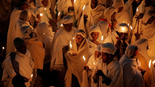 Des orthodoxes éthiopiens drapés de blanc célèbrent la veille de Noël à l'église Bete Maryam, éclairés à la chandelle. Des orthodoxes éthiopiens drapés de blanc célèbrent la veille de Noël à l'église Bete Maryam, éclairés à la chandelle.